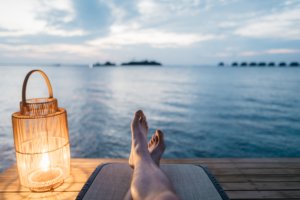 man sitting on dock overlooking water with lamp next to feet