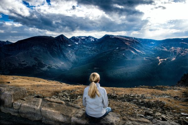 woman sitting on rock overlooking a mountain
