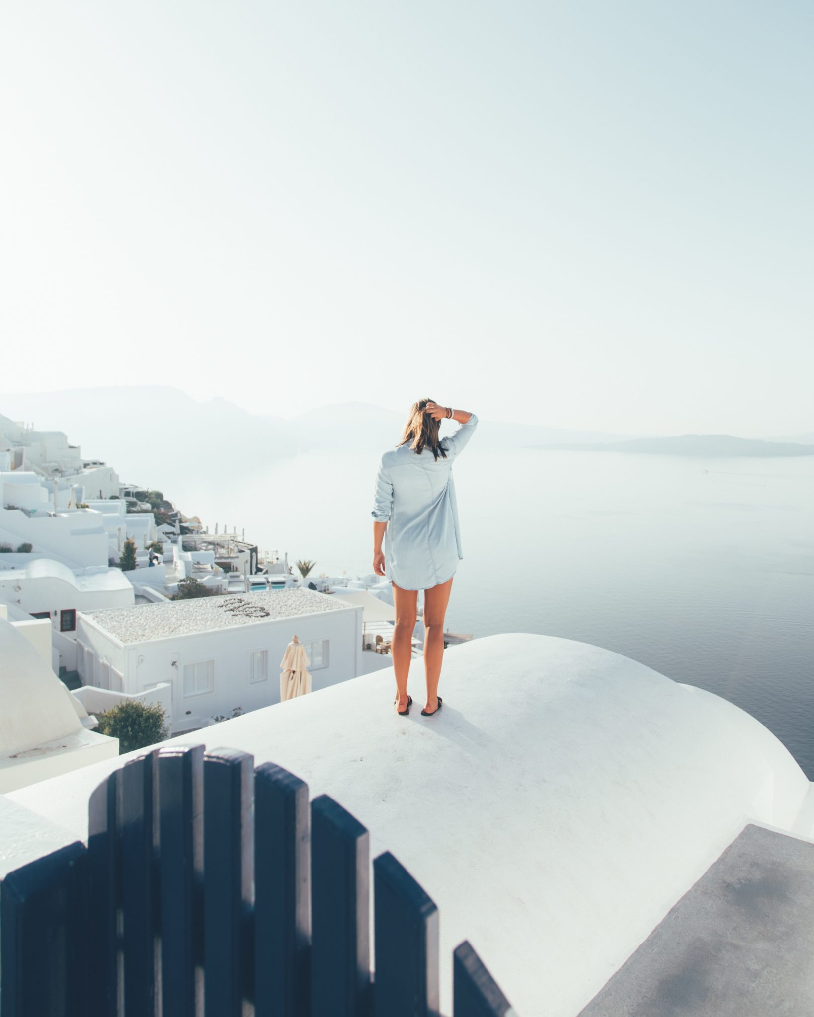 woman standing on top of building in santorini