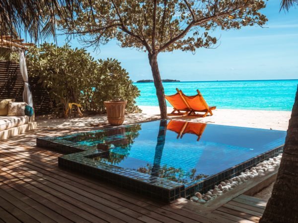 Maldives villa with orange beach chairs and pool out back facing the Indian Ocean