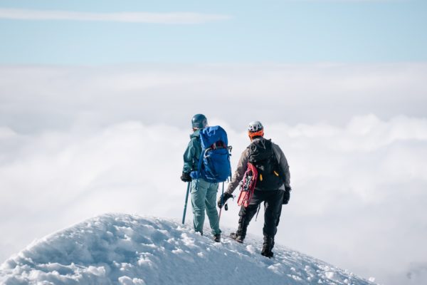 two mountain climbers at the top of a snowy mountain top