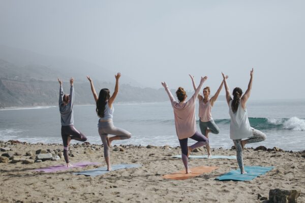 group of women doing a yoga retreat at the beach on a cloudy day