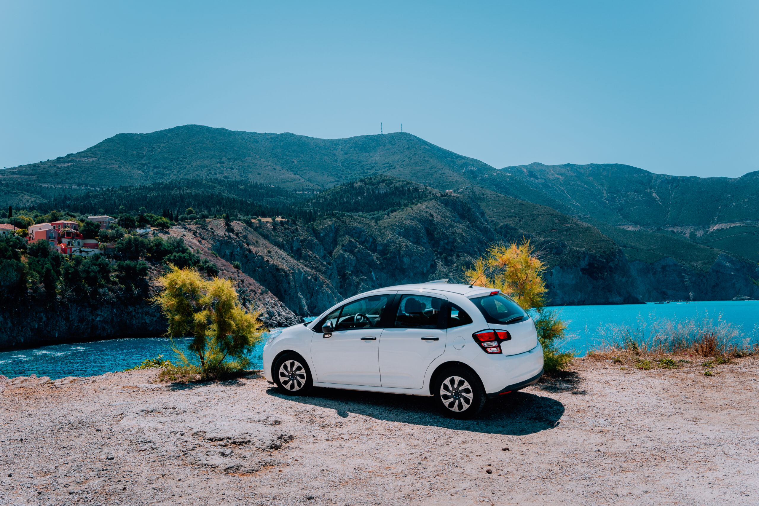 car sitting next to a beautiful scenic viewpoint of mountains next to water