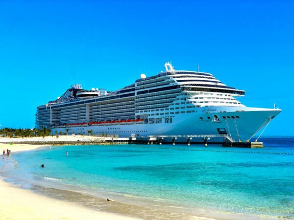 cruise ship in water near port and beach with turquoise blue water and very blue sky