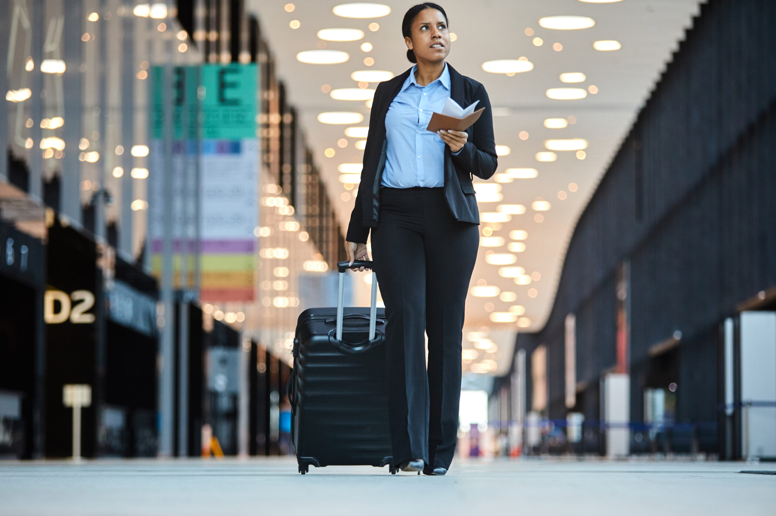 lady wheeling a suitcase behind her and holding her passport open