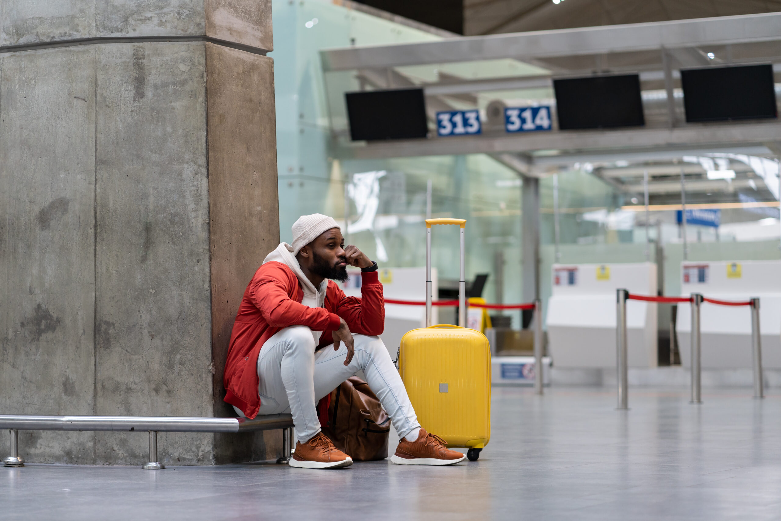 man sitting in airport on the phone with suitcase next to him