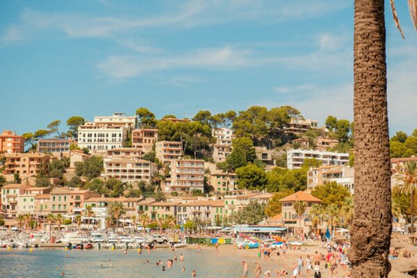 beach town in spain with lots of people swimming in water and on beach