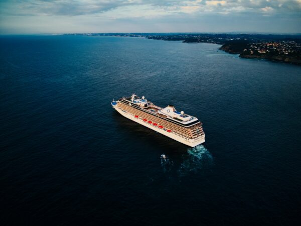 ocean line cruise ship in the middle of the dark blue ocean with land off in the distance