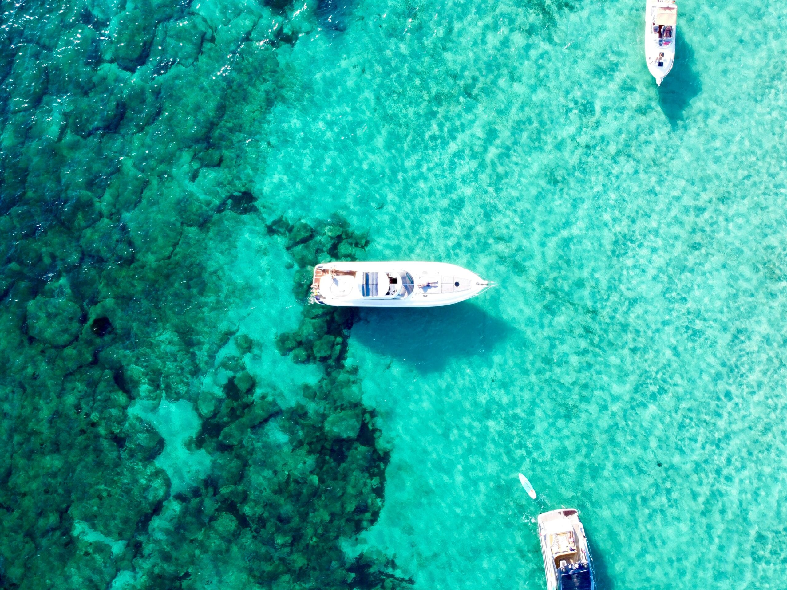 white yacht boats on turquoise clear green water