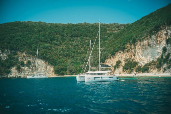 catamaran boats anchored next to cliffs covered in greenery