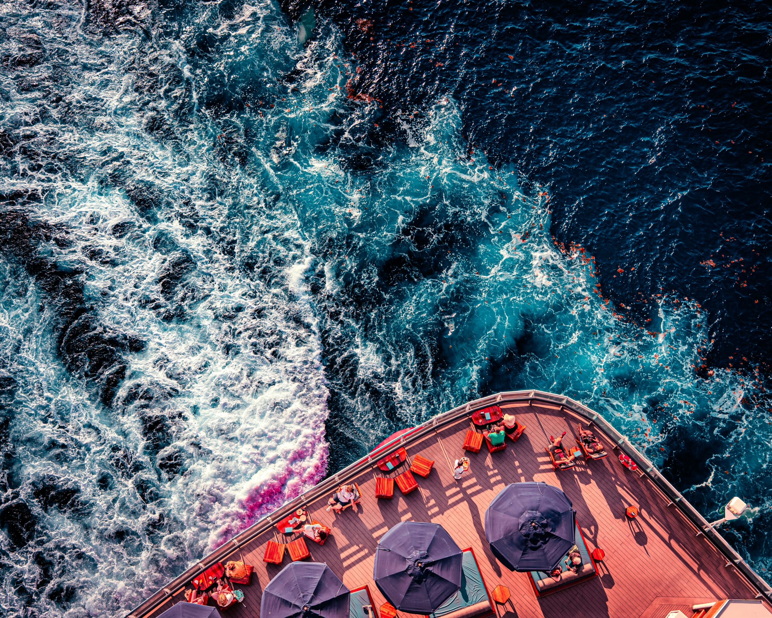 back of a cruise ship deck with dining and the ocean water flowing behind the ship