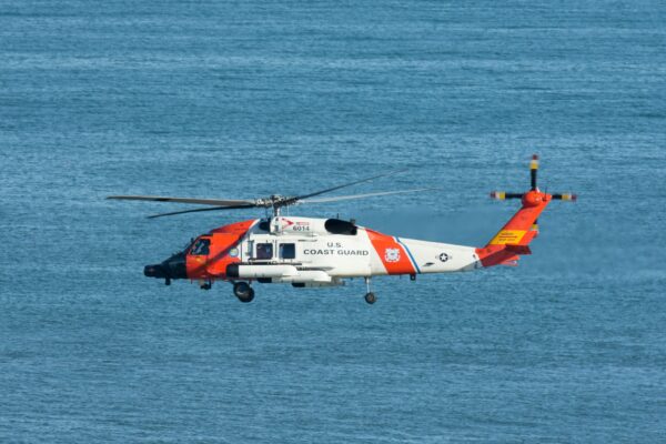 coast guard helicopter flying over blue ocean water