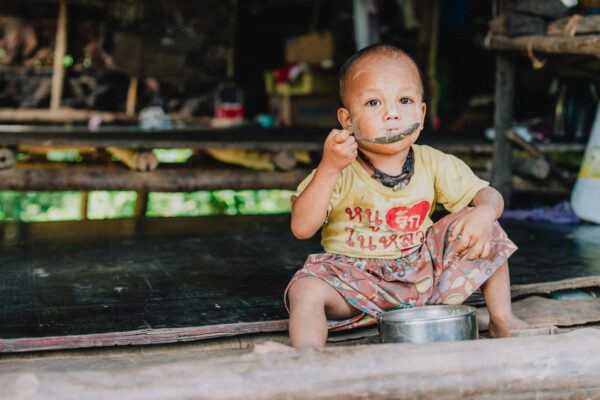 a child refugee eating a meal sponsored by Yonder Travel Insurance through policy purchases
