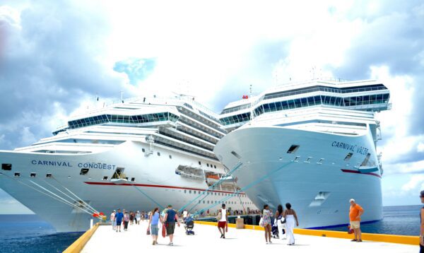 two carnival cruise ships docked next to each other with people walking on the dock