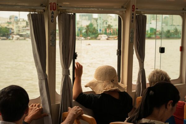tourists on a water taxi looking out the window at the water and cityscape