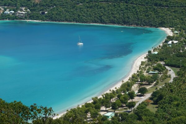 Beautiful white sand beach and crystal clear water in the Caribbean, plus a sailing charter catamaran in the US Virgin Islands