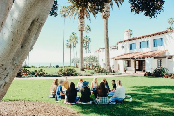 group of young ladies sitting in a circle on the grass in a warm destination with palm trees