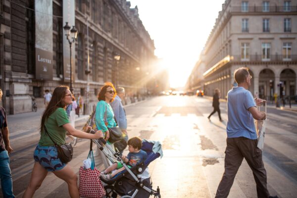 a multi-generational family in Europe crossing the street with a child in a stroller