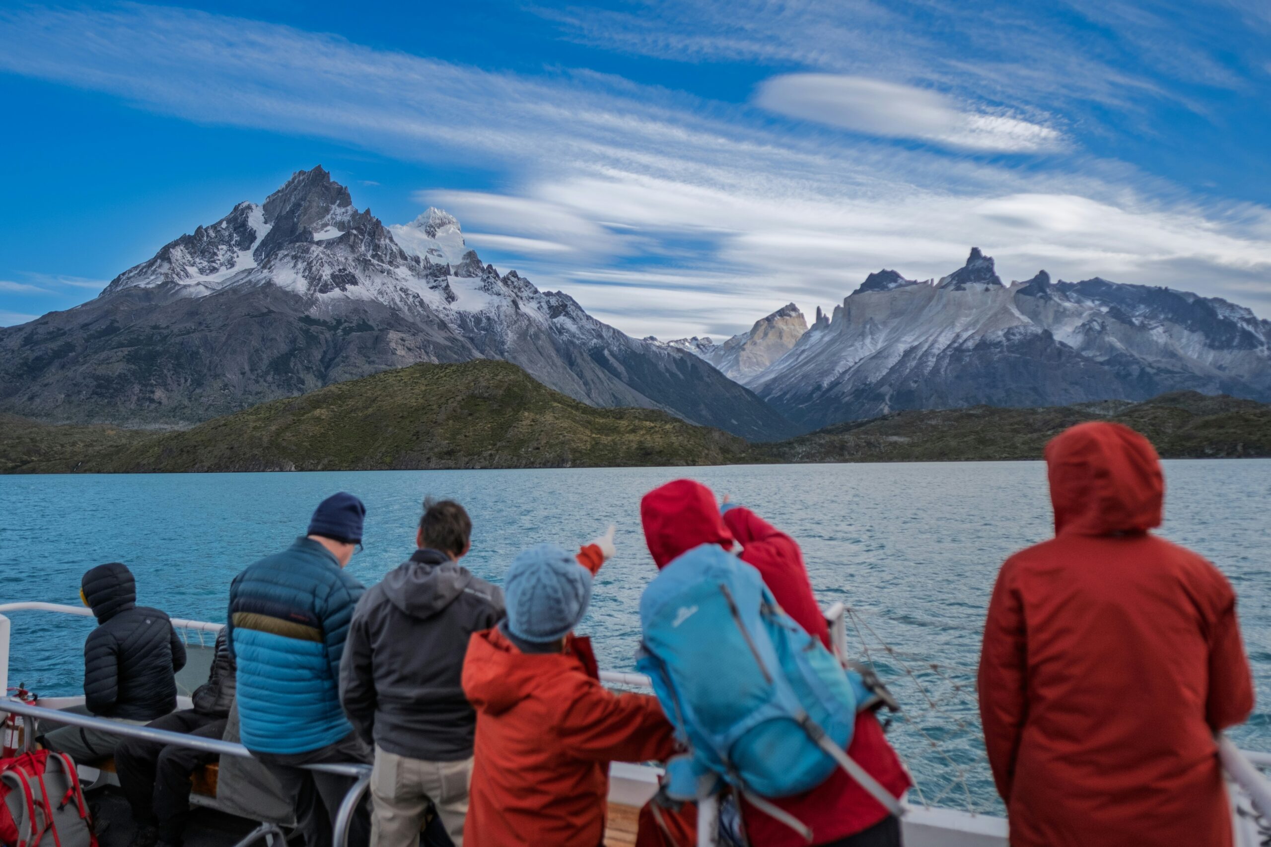 a family group dressed in winter gear looking at mountains from a boat