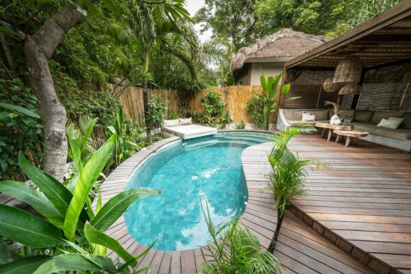 beautiful private back area of a vacation rental with a pool and deck area enclosed by fence and greenery