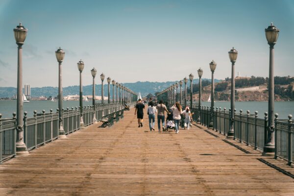 group of people walking down a bridge next to water