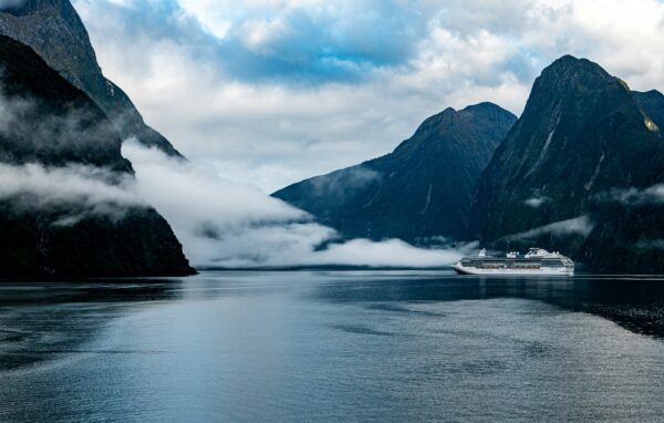 cruise ship sailing through New Zealand with moody mountains in the background