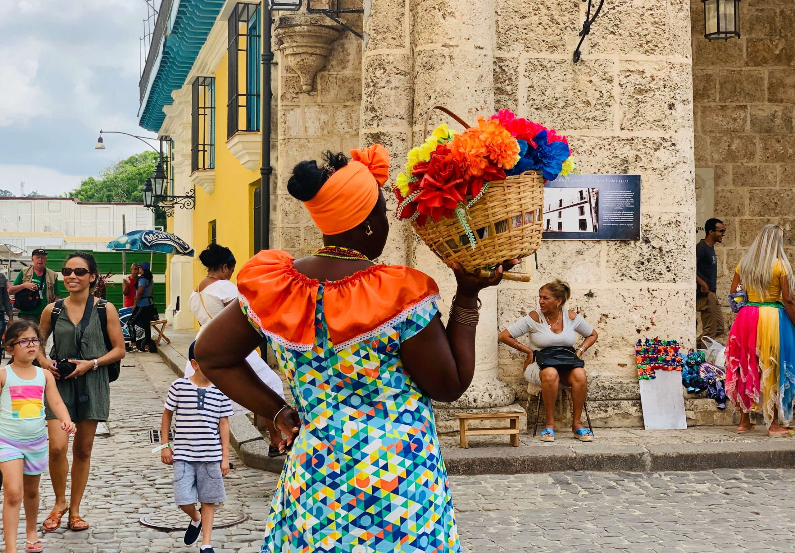 woman holding goods in a basket wearing bright colors in Cuba